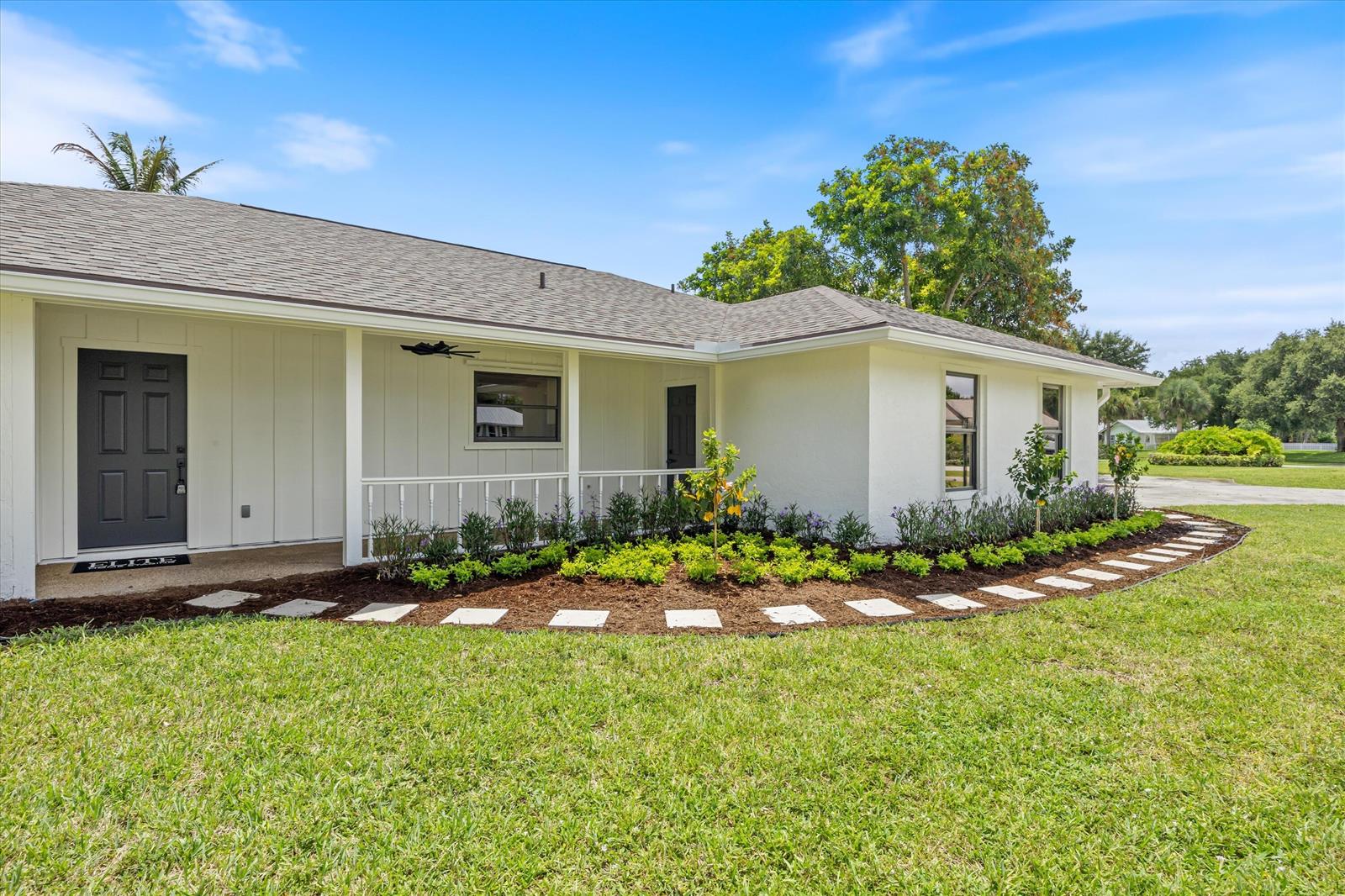 A white house with a dark front door and a curved stone walkway in front — 621 NE Town Terrace, Jensen Beach FL 34957, JENSEN BEACH, FL
