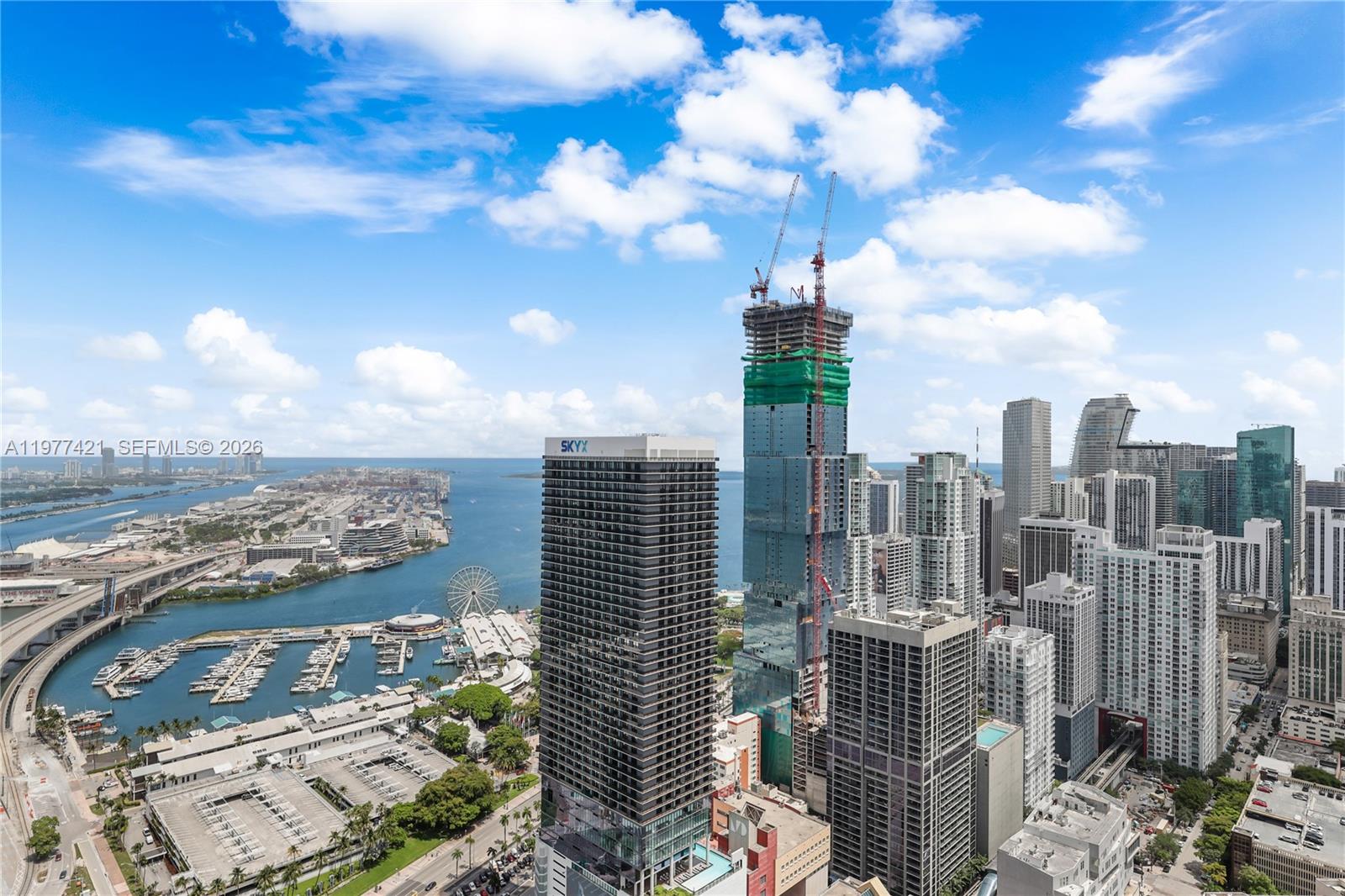 An aerial view shows a dense city skyline with a prominent skyscraper under construction — 159 NE 6th St # 5115, Miami FL 33132, MIAMI, FL