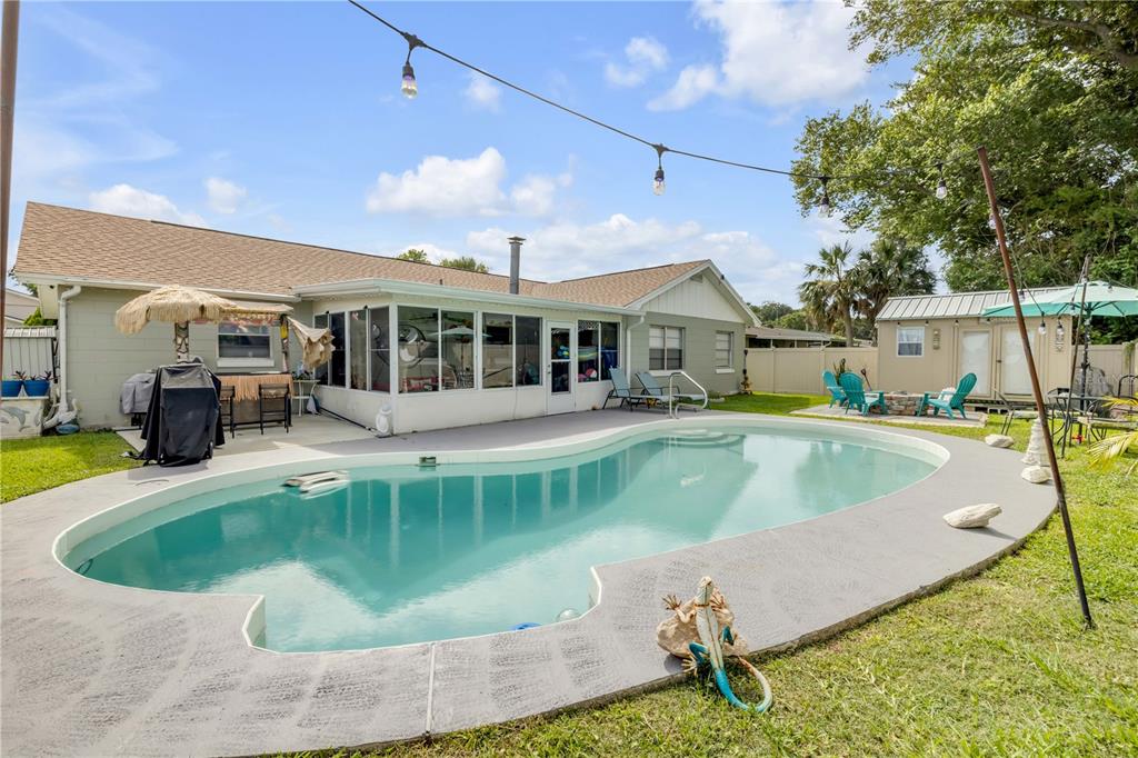 A backyard features a swimming pool, a patio with string lights, and a storage shed — 2952 CARRIAGE DRIVE, SOUTH DAYTONA, FL