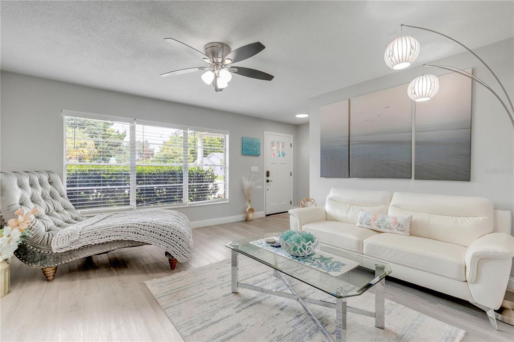 A living room features a white sofa, a tufted chaise lounge, and a glass coffee table — 2952 CARRIAGE DRIVE, SOUTH DAYTONA, FL