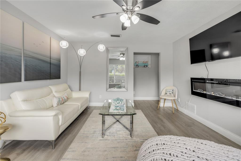 A living room features a white sofa, glass coffee table, fireplace, and light wood flooring — 2952 CARRIAGE DRIVE, SOUTH DAYTONA, FL