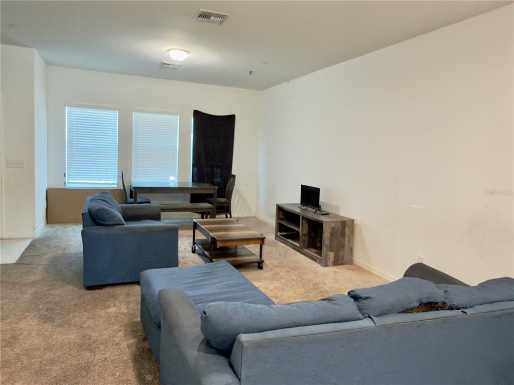 A living room with blue sofas, a coffee table, and a dining set on carpet — 3139 AZOLLA STREET, ORLANDO, FL