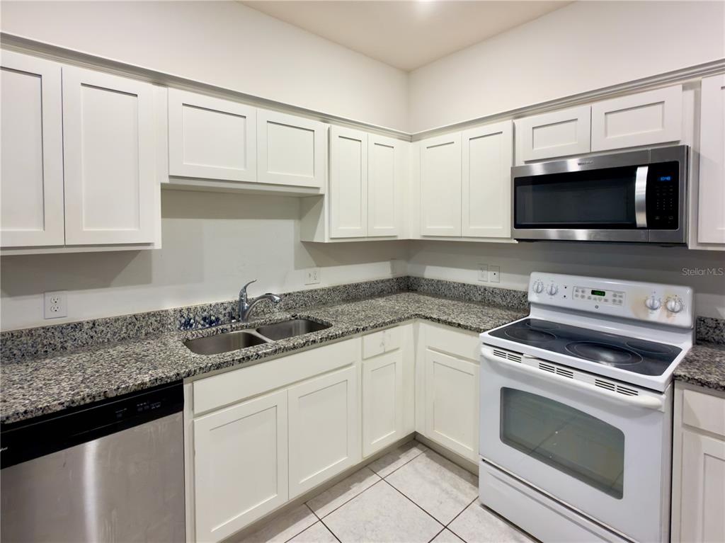 A kitchen features white cabinets, granite countertops, a stainless steel dishwasher, and a white stove — 3139 AZOLLA STREET, ORLANDO, FL