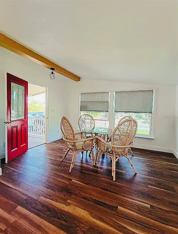 A dining area features a glass table, four wicker chairs, wood flooring, and a red door — 9128 OTTER PASS, TAMPA, FL