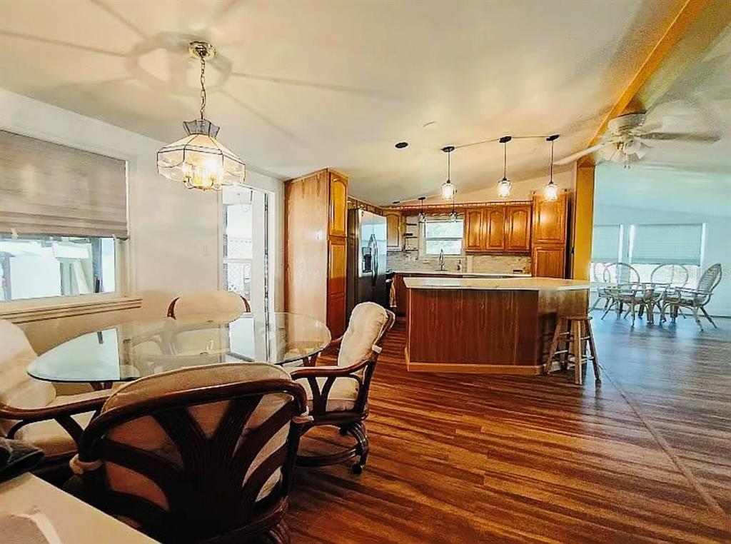 A dining area with a glass table leads into a kitchen featuring wood cabinets — 9128 OTTER PASS, TAMPA, FL