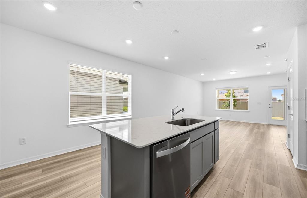 A kitchen island with a stainless steel dishwasher sits in a room with light flooring — 1041 WENAHA COURT, ZEPHYRHILLS, FL