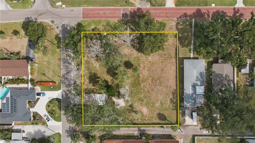 An aerial view shows a vacant, rectangular residential lot outlined in yellow between two houses — 698 VILLAGRANDE AVENUE S, ST PETERSBURG, FL