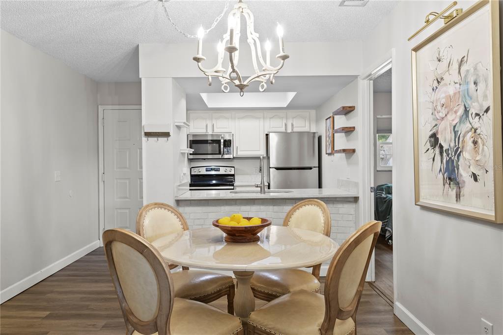 A dining area with a round table and chairs sits in front of a kitchen — 4506 S OAK DRIVE UNIT S92, TAMPA, FL