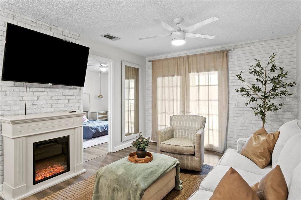 A living room features a white brick fireplace, a ceiling fan, and a beige armchair — 4506 S OAK DRIVE UNIT S92, TAMPA, FL