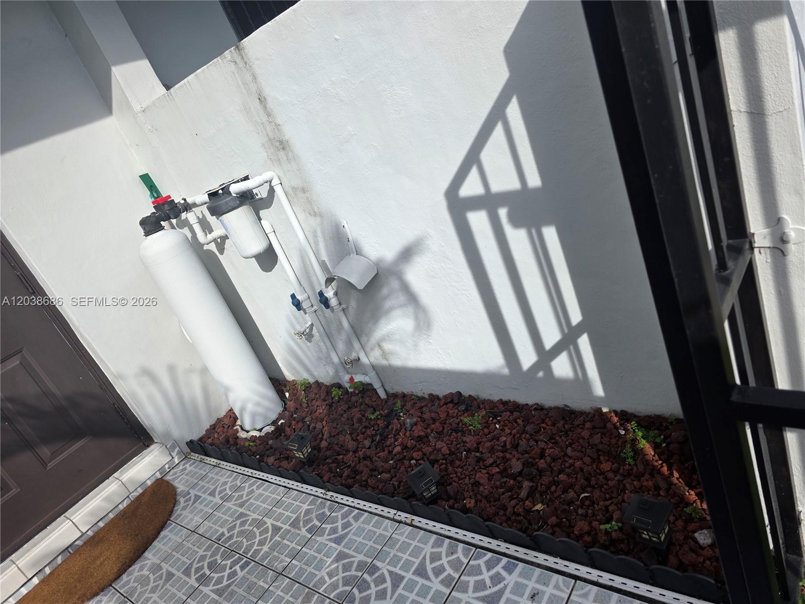 A water filtration system is mounted on an exterior wall above a rock garden — 8000 SW 152nd Ave # 115, Miami FL 33193, MIAMI, FL