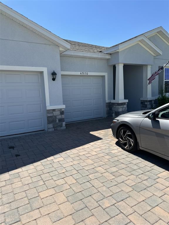 A gray house exterior features a two-car garage, stone accents, and a paved driveway — 4970 NW 39TH LOOP, OCALA, FL