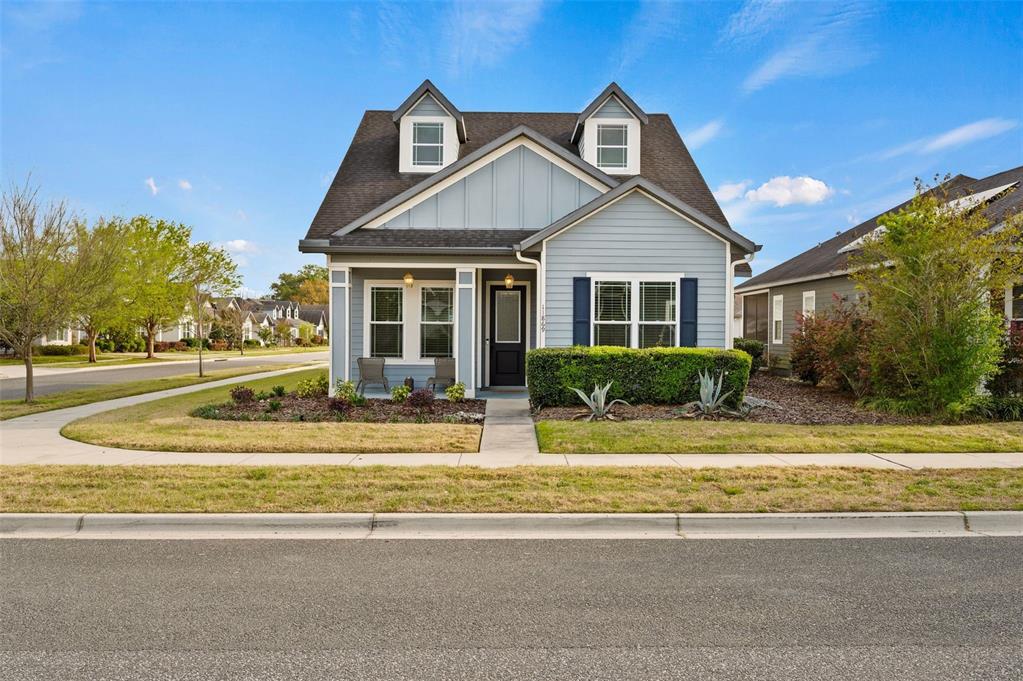 A light blue, single-story house with a dark roof, two dormer windows, and a front porch — 11869 SW 28TH AVENUE, GAINESVILLE, FL