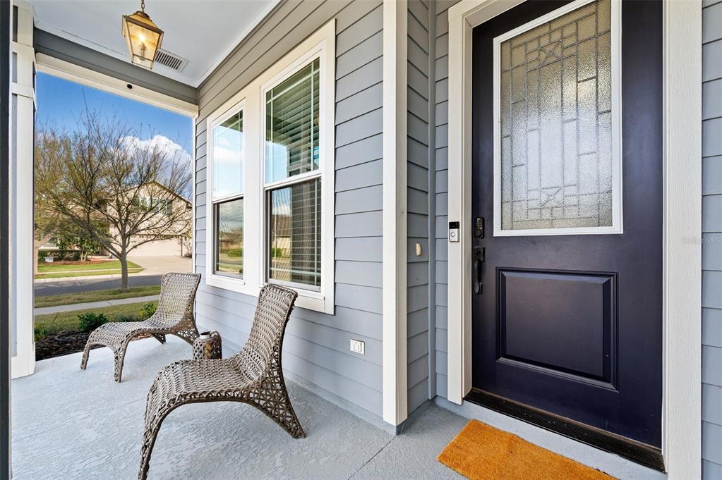A covered front porch features two wicker chairs, light blue siding, and a dark front door — 11869 SW 28TH AVENUE, GAINESVILLE, FL