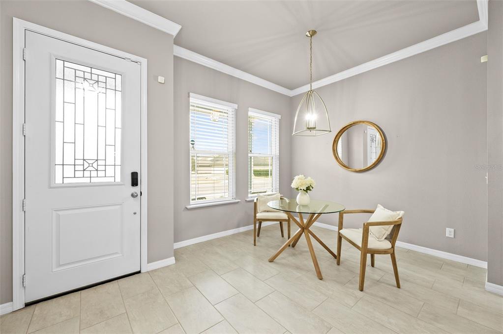 A dining area features a glass-top table, two chairs, a pendant light, and tile flooring — 11869 SW 28TH AVENUE, GAINESVILLE, FL