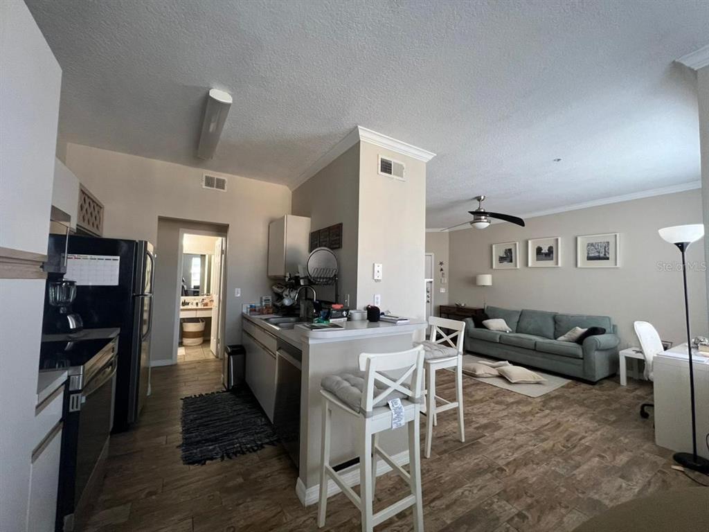 An open-concept kitchen with a breakfast bar overlooks a living room with a sofa — 2632 ROBERT TRENT JONES DRIVE UNIT 134, ORLANDO, FL