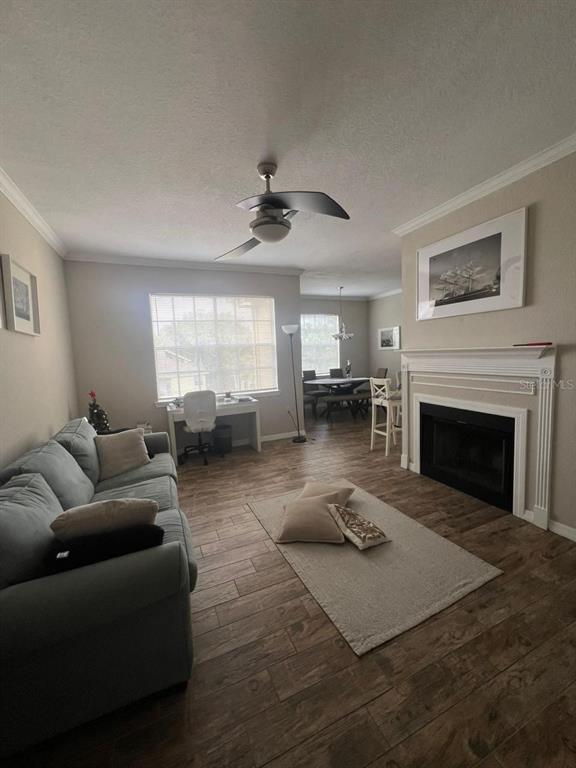 A living room features a gray sofa, a fireplace, a desk, and wood-look tile flooring — 2632 ROBERT TRENT JONES DRIVE UNIT 134, ORLANDO, FL