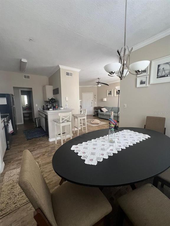 A dining area with a black oval table sits adjacent to a kitchen with bar seating — 2632 ROBERT TRENT JONES DRIVE UNIT 134, ORLANDO, FL