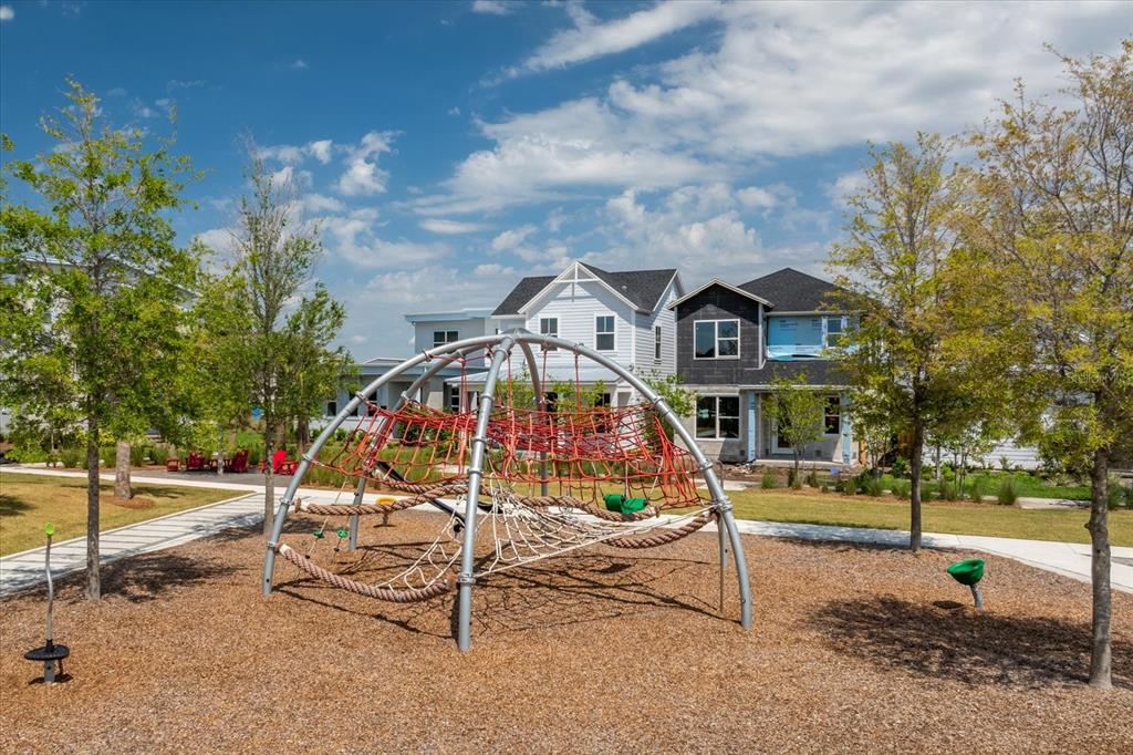 A playground with a rope climbing dome sits in front of two suburban houses — 10017 PEEBLES STREET, ORLANDO, FL