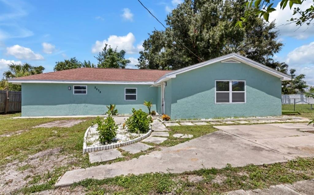 A light green, single-story house with a brown roof, concrete driveway, and a landscaped walkway — 2839 OLYMPIC STREET, SARASOTA, FL