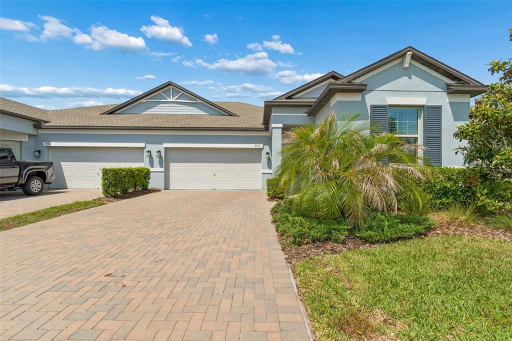 A single-story house with a paved driveway, two garage doors, and a palm tree — 9911 CAMPANULA COURT, LAND O LAKES, FL