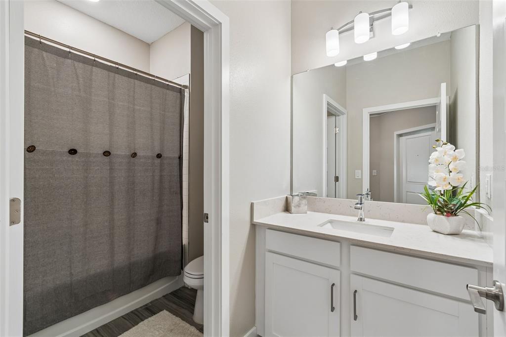 A bathroom features a white vanity, a large mirror, and a shower with a gray curtain — 9911 CAMPANULA COURT, LAND O LAKES, FL