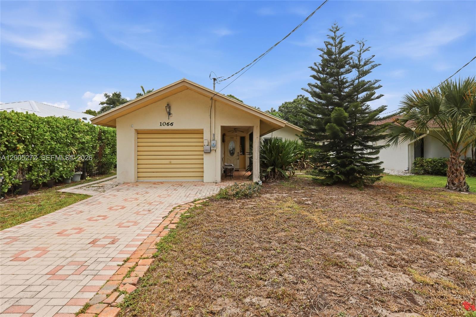 A single-story house with a beige exterior, a garage, and a brick-paved driveway — 1066 Highlands Dr, Naples FL 34103, NAPLES, FL