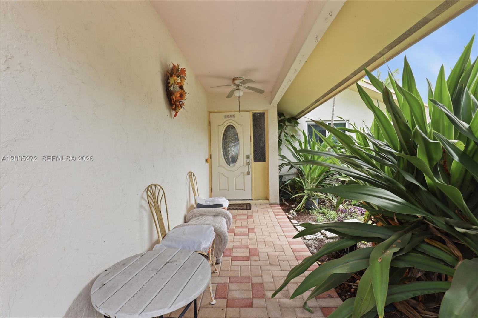 A covered front porch features a paved walkway, outdoor seating, and a ceiling fan — 1066 Highlands Dr, Naples FL 34103, NAPLES, FL