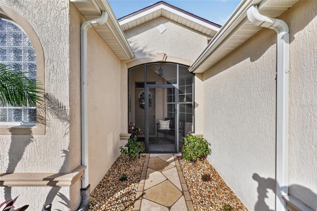 A stone walkway leads to a screened-in front entryway with a beige stucco exterior — 1092 SW 159TH STREET, OCALA, FL