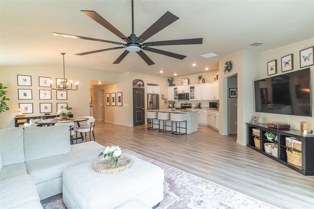 An open-concept living room, dining area, and kitchen with light wood flooring and white cabinetry — 615 VALRI PARK DRIVE, VALRICO, FL