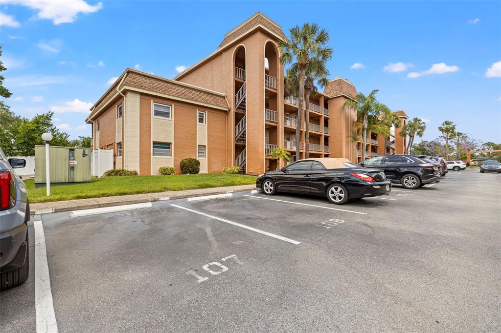 A multi-story tan apartment building with a parking lot in the foreground — 12760 INDIAN ROCKS ROAD UNIT 107, LARGO, FL