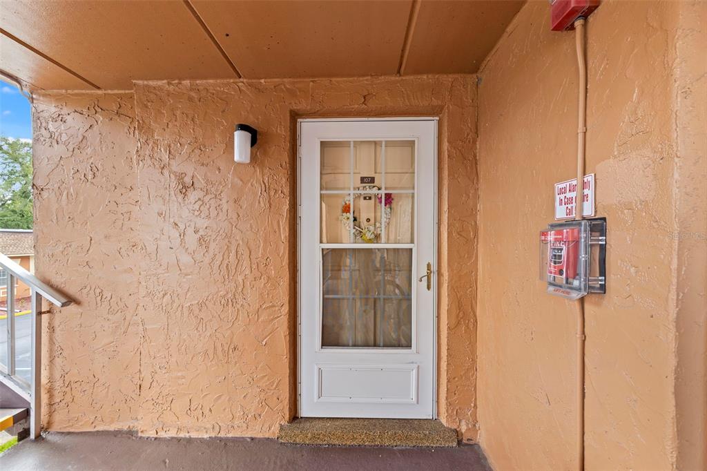 A white storm door with a floral wreath leads into a unit with textured walls — 12760 INDIAN ROCKS ROAD UNIT 107, LARGO, FL