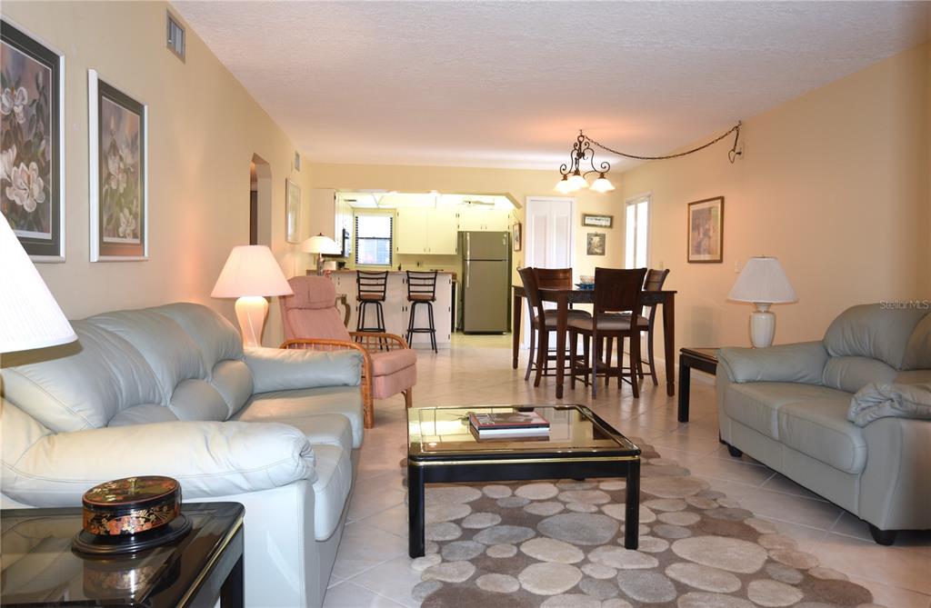 A living room with two light-colored sofas, a glass coffee table, and a dining area — 5400 34TH STREET W UNIT D6, BRADENTON, FL