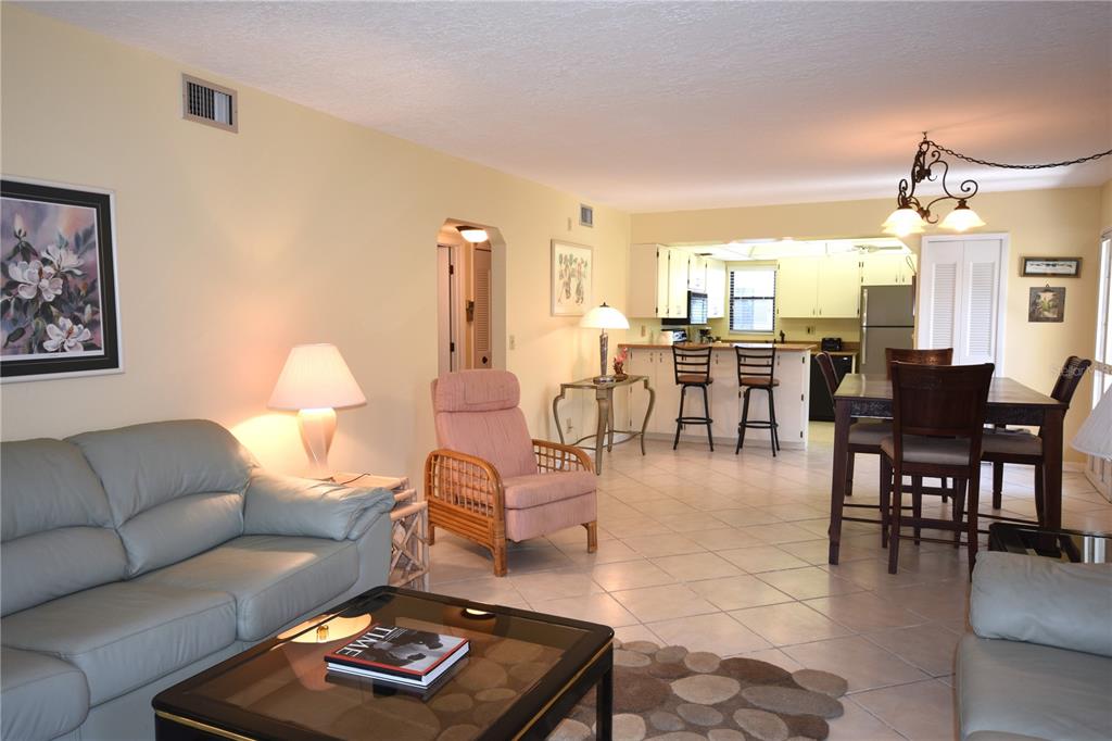 An open-concept living and dining area with tile flooring, a kitchen island, and neutral walls — 5400 34TH STREET W UNIT D6, BRADENTON, FL
