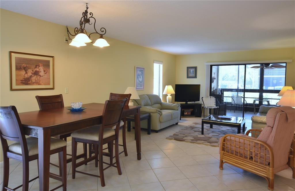 A dining area and living room with tile floors, a chandelier, and sliding glass doors — 5400 34TH STREET W UNIT D6, BRADENTON, FL