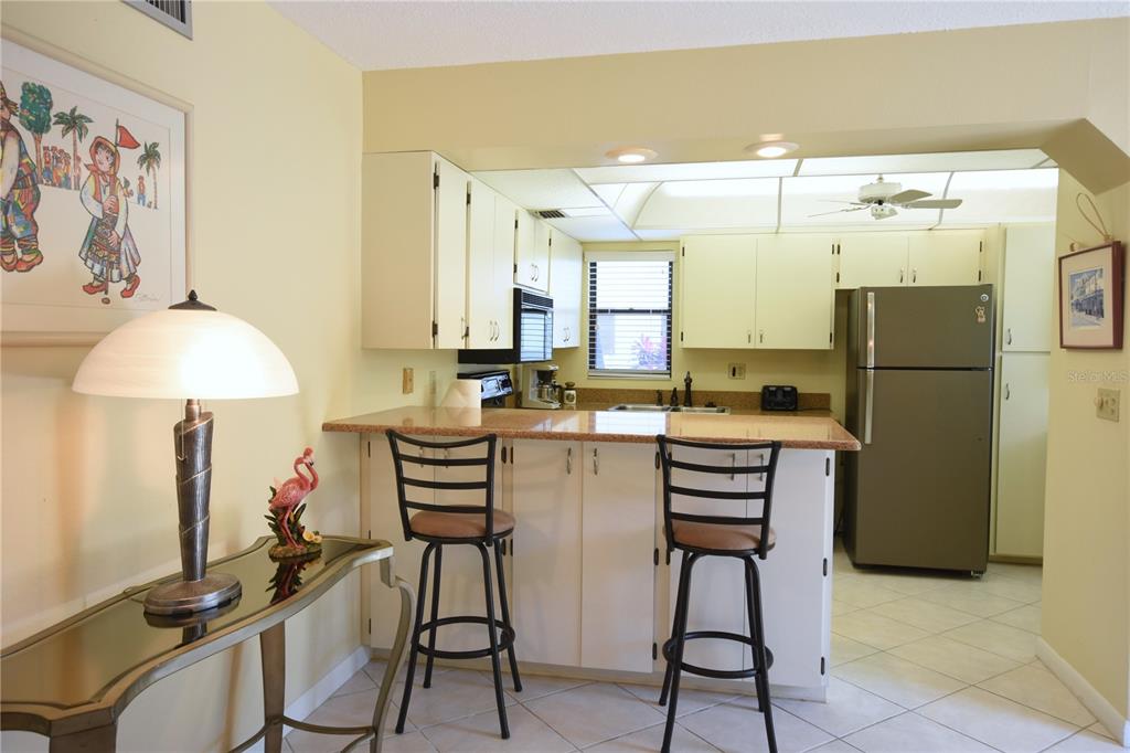 A kitchen with white cabinets, a breakfast bar, and a stainless steel refrigerator — 5400 34TH STREET W UNIT D6, BRADENTON, FL