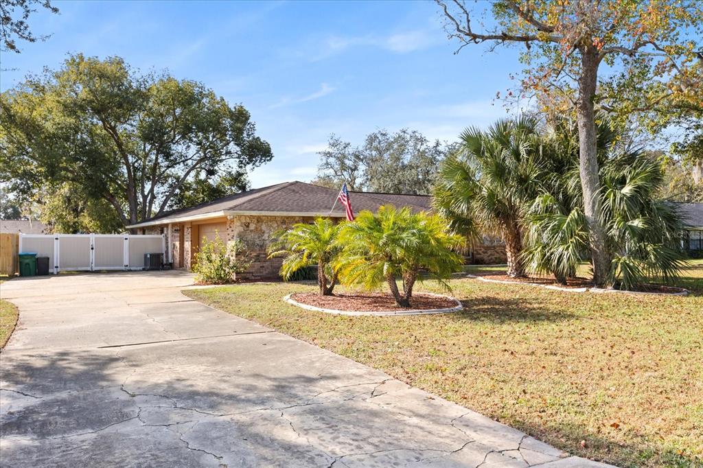 A single-story house with a stone facade, a concrete driveway, and palm trees in front — 2047 ROCKY HILL DRIVE, DELTONA, FL