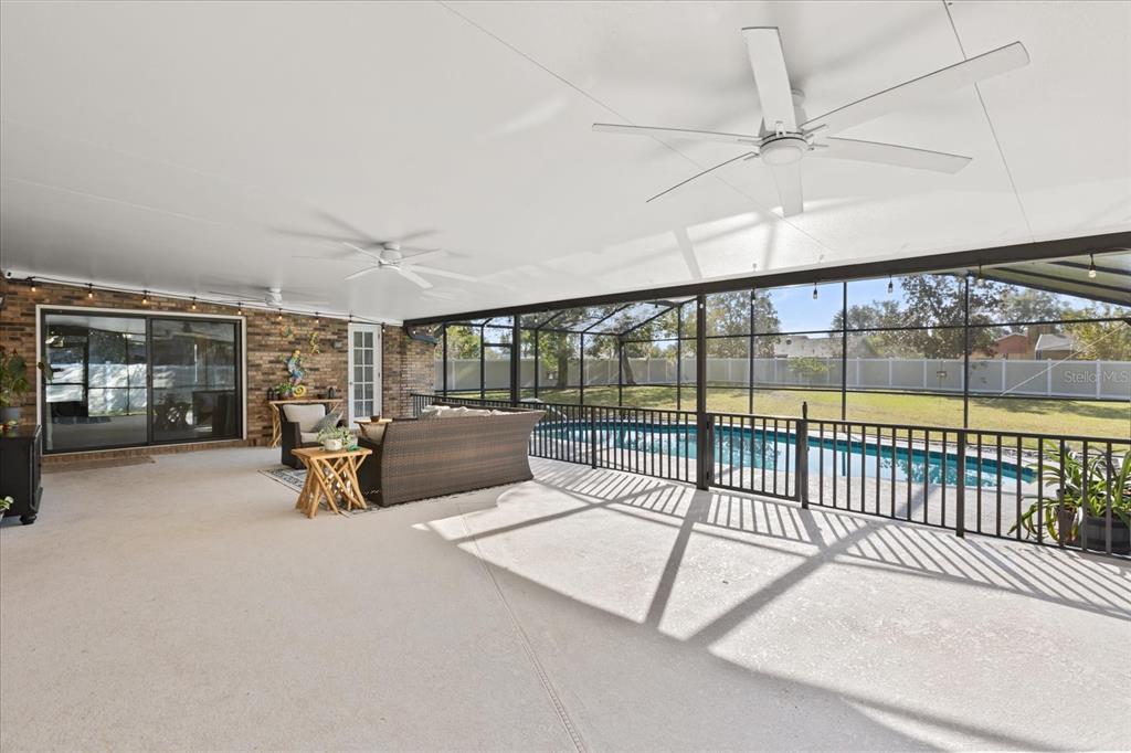 A covered patio features a ceiling fan, wicker furniture, and a view of a swimming pool — 2047 ROCKY HILL DRIVE, DELTONA, FL