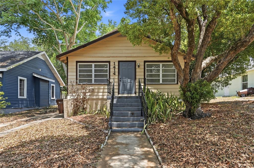 A single-story house with beige siding, a gray front door, and concrete steps — 1414 JOHNS AVENUE, HAINES CITY, FL