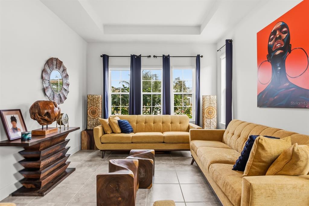 A living room features two mustard-colored sofas, a wooden console table, and large wall art — 3963 CARRICK BEND DRIVE, KISSIMMEE, FL