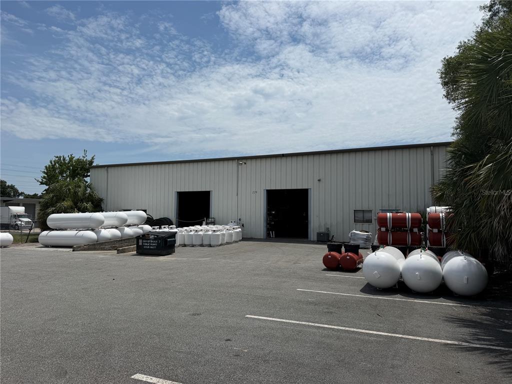 An industrial building exterior features a parking lot filled with numerous white propane storage tanks — 229 SW 54TH COURT, OCALA, FL