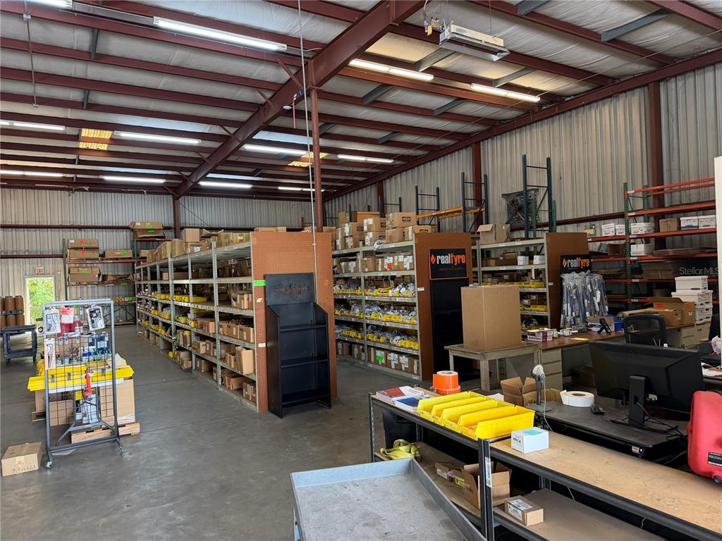 An industrial warehouse interior features metal shelving units, storage racks, and a workspace with desks — 229 SW 54TH COURT, OCALA, FL