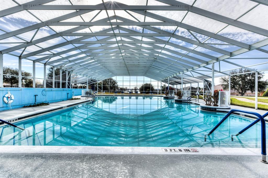 A large, rectangular swimming pool is enclosed by a white metal screen structure — 6274 SAILBOAT AVENUE, TAVARES, FL