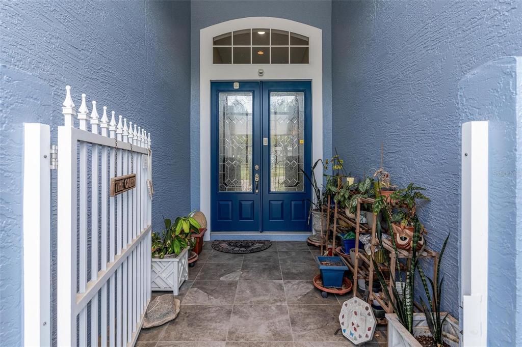 A blue front door with glass panels sits at the end of a tiled entryway — 6274 SAILBOAT AVENUE, TAVARES, FL