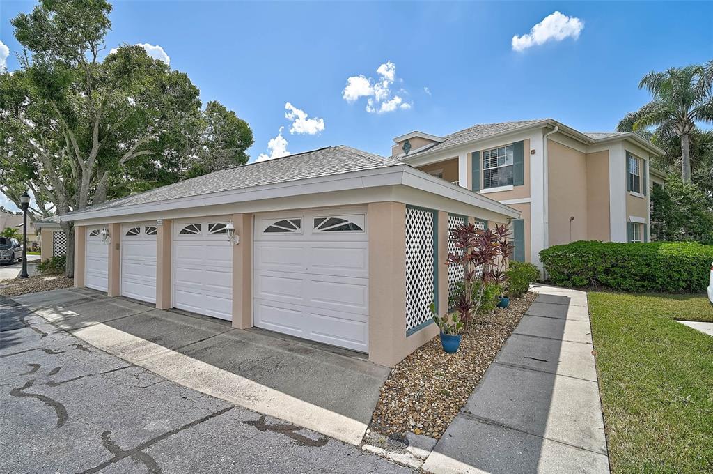 A row of four white garage doors attached to a tan two-story residential building — 4705 SAND TRAP STREET CIRCLE E UNIT 106, BRADENTON, FL