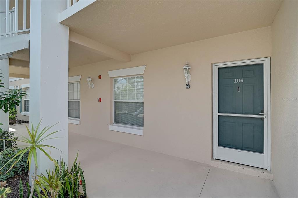 A covered entryway features a beige wall, a screen door labeled 106, and windows — 4705 SAND TRAP STREET CIRCLE E UNIT 106, BRADENTON, FL