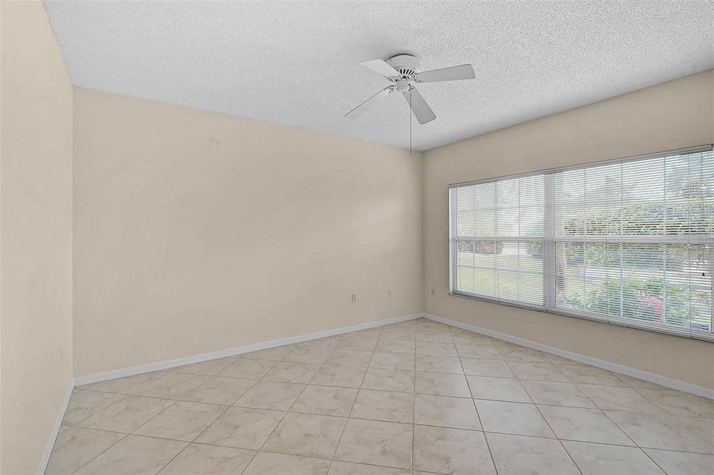 An empty room features beige walls, light-colored tile flooring, and a ceiling fan — 4705 SAND TRAP STREET CIRCLE E UNIT 106, BRADENTON, FL