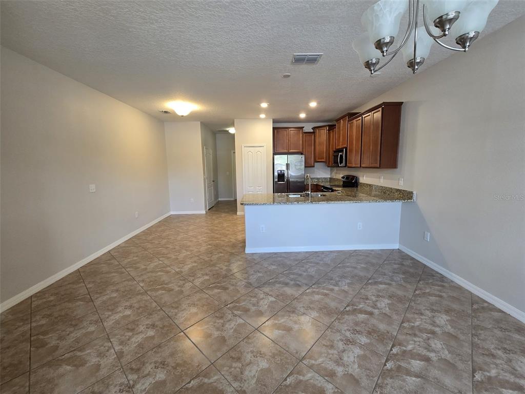 An open-concept kitchen with dark wood cabinets and a granite breakfast bar overlooks a tiled room — 4252 FENNWOOD COURT, WESLEY CHAPEL, FL