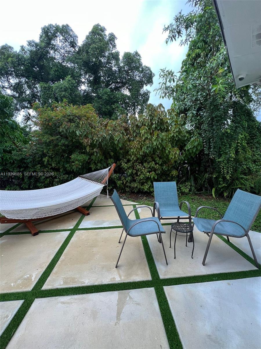 A patio features large concrete pavers with grass joints, a hammock, and three chairs — 1110 NE 119th, Biscayne Park FL 33161, BISCAYNE PARK, FL