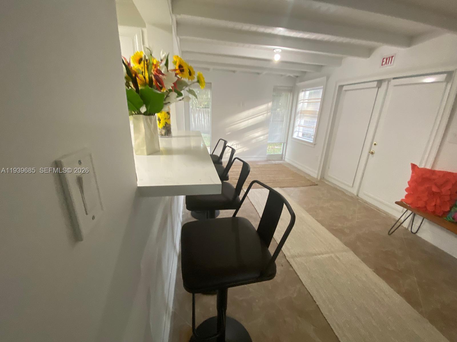 A white bar counter with stools sits in a room featuring white beamed ceilings — 1110 NE 119th, Biscayne Park FL 33161, BISCAYNE PARK, FL
