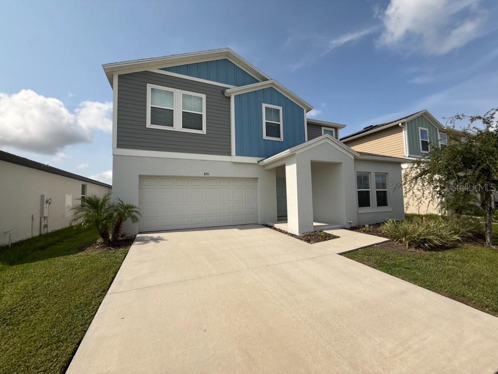 A two-story house with a concrete driveway, a two-car garage, and blue and gray siding — 870 SAND SEA PLACE, HAINES CITY, FL